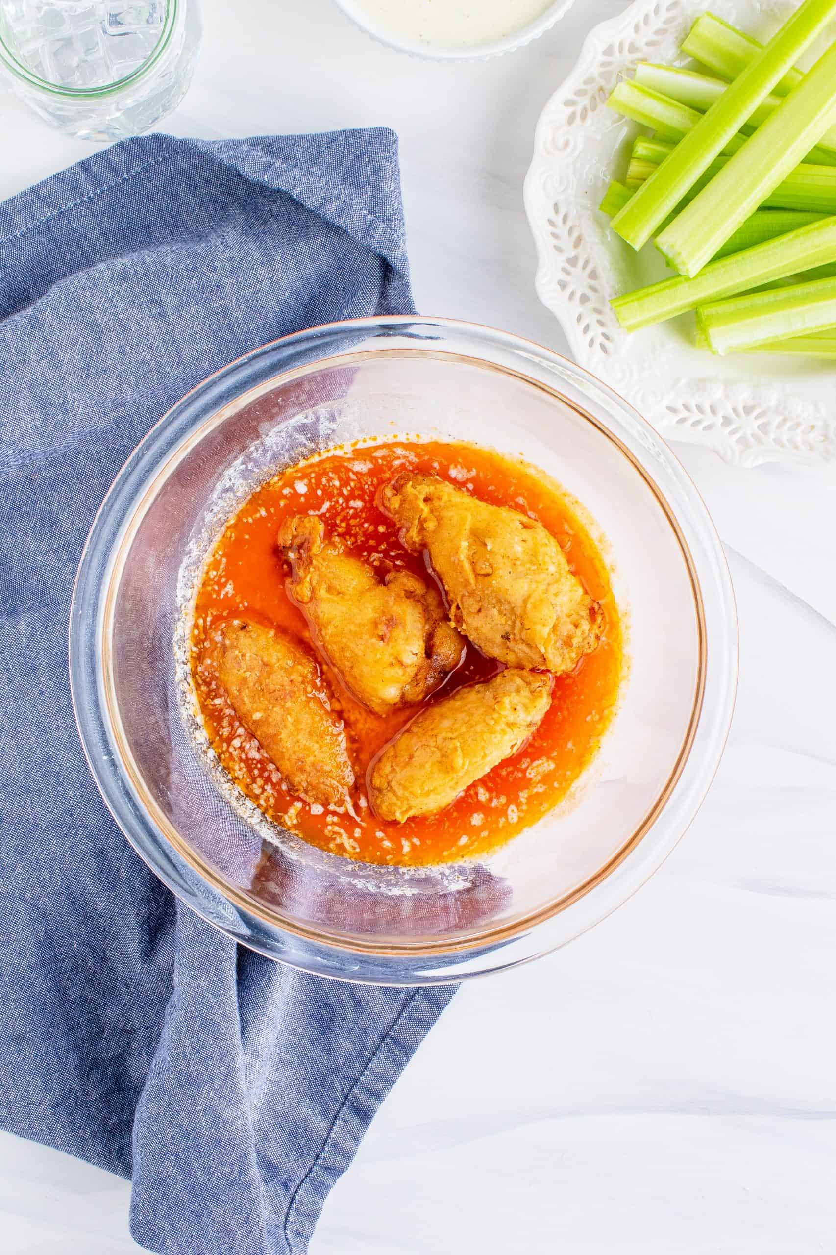 fried chicken wings shown in a bowl with hot sauce and melted butter.