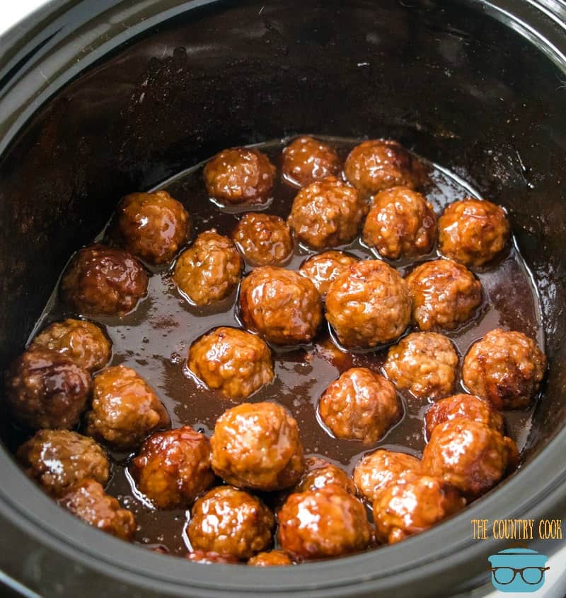 Easy crock pot glazed meatballs shown fully cooked in a round, black crock pot.
