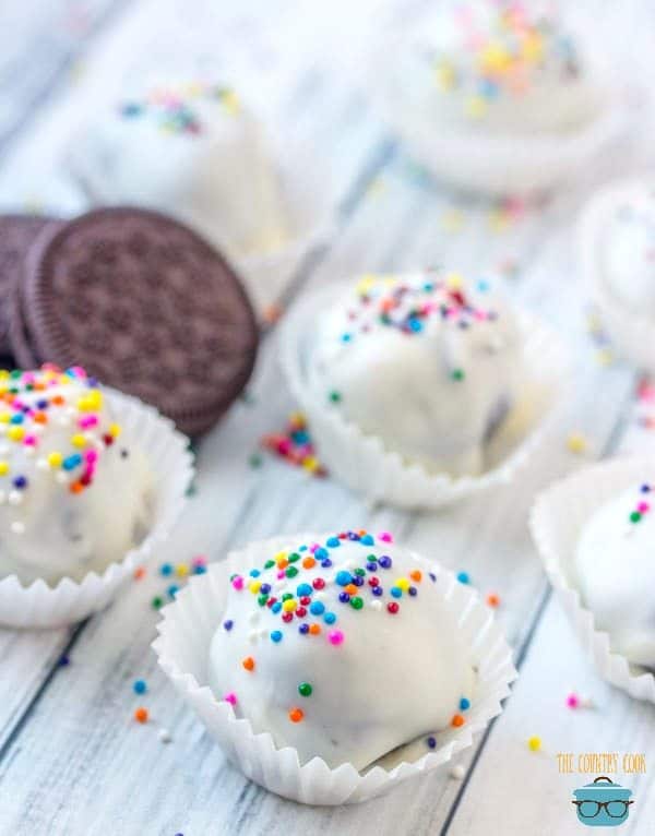 Oreo Cookie Balls covered in white vanilla chocolate almond bark in mini cupcake wrappers topped with colorful sprinkles