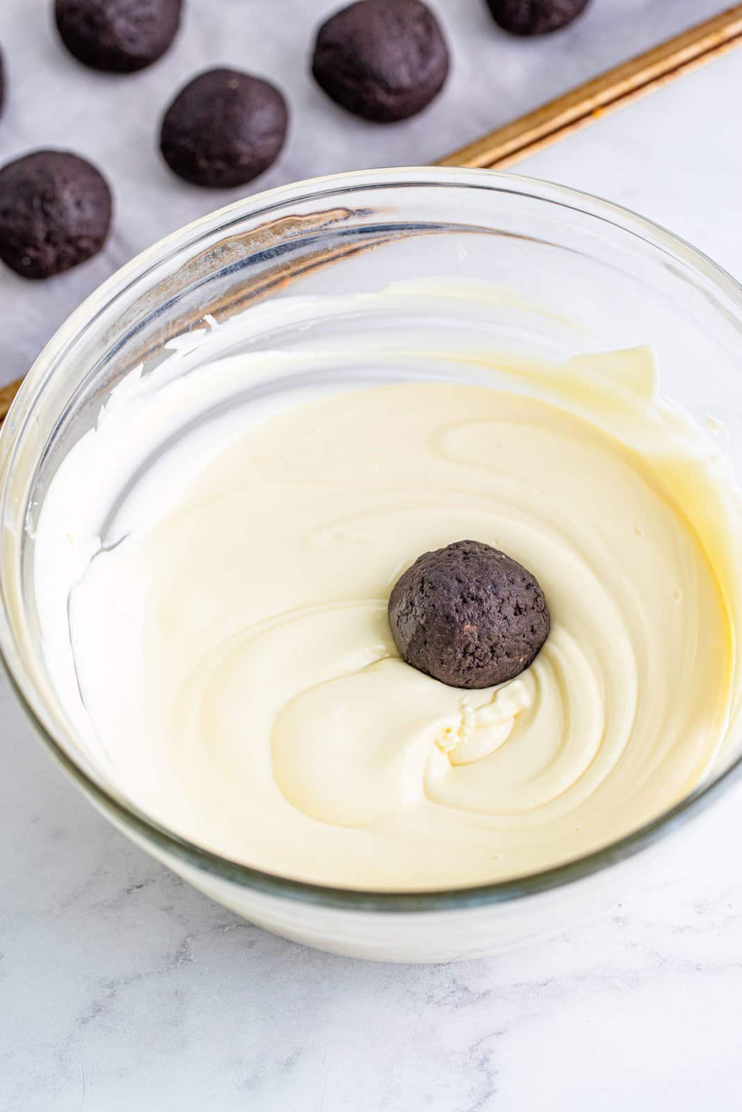 dipping cookie ball into melted white chocolate.