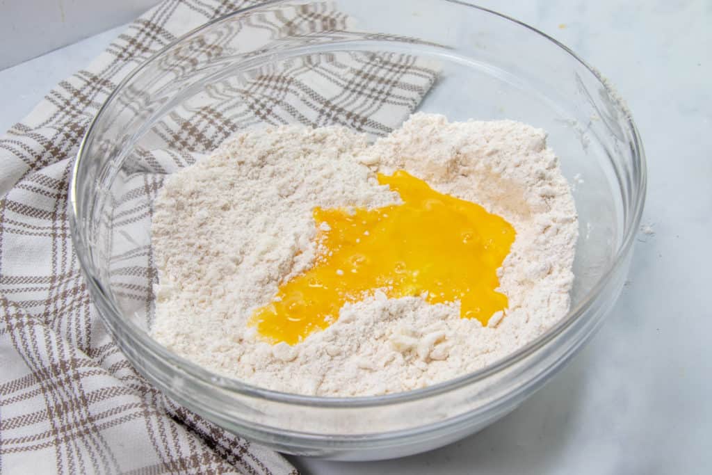 beaten eggs poured on top of flour and shortening mixture in a clear bowl