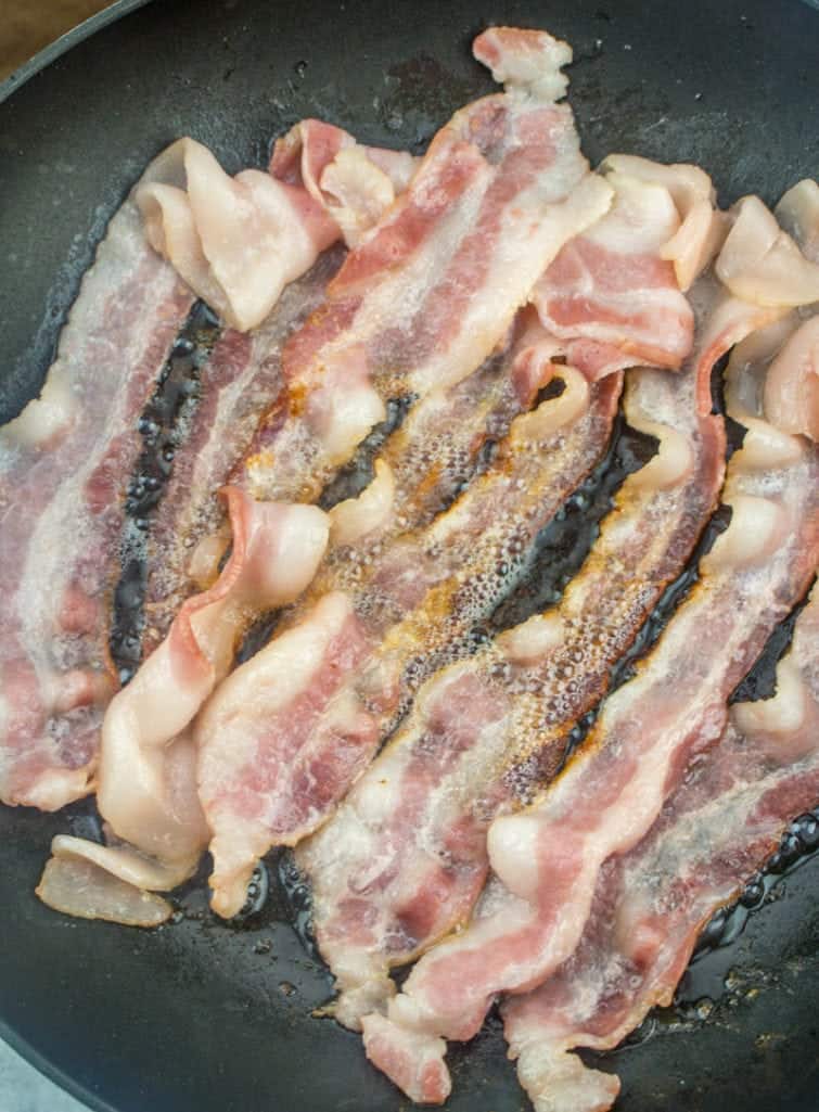 cooking strips of bacon in a large skillet
