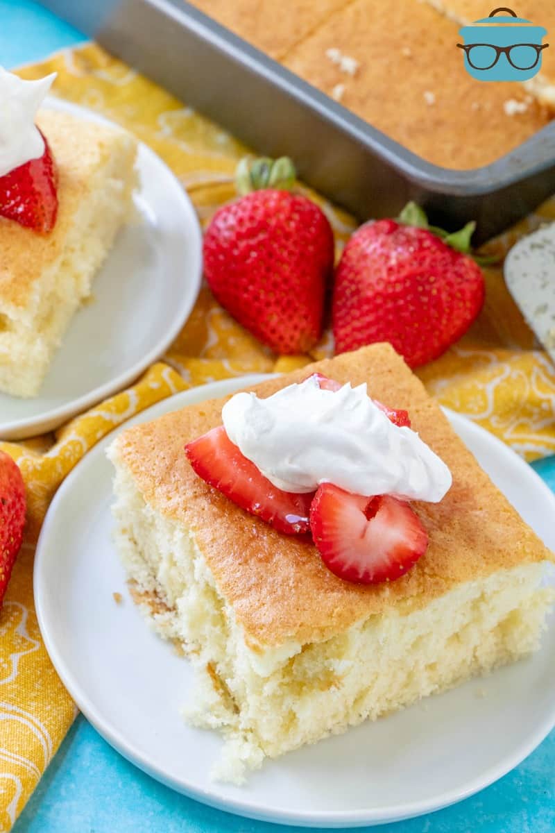 Hot Milk Sponge Cake served on a plate with fresh strawberries and whipped cream.