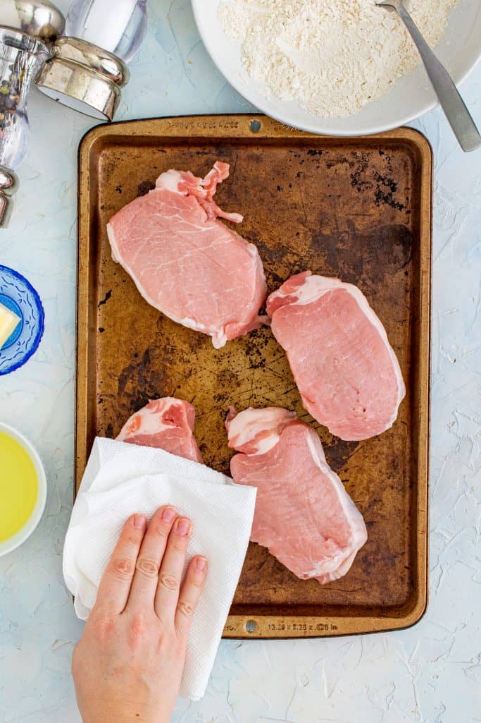 patting pork chops with a paper towel.