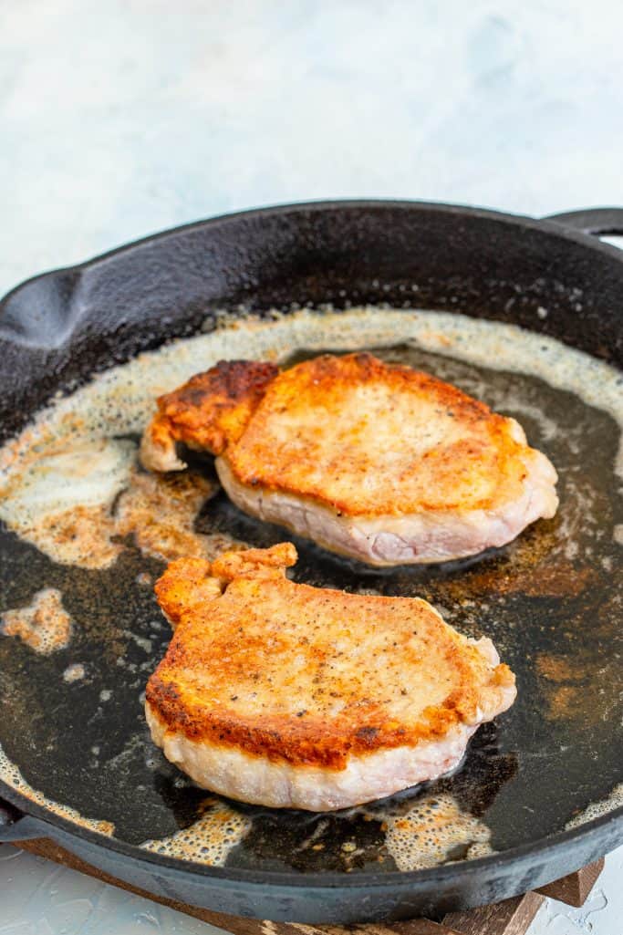 browned pork chops in a cast iron skillet.
