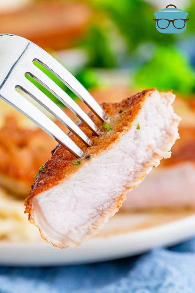 a slice of cooked pork chop shown on a fork.