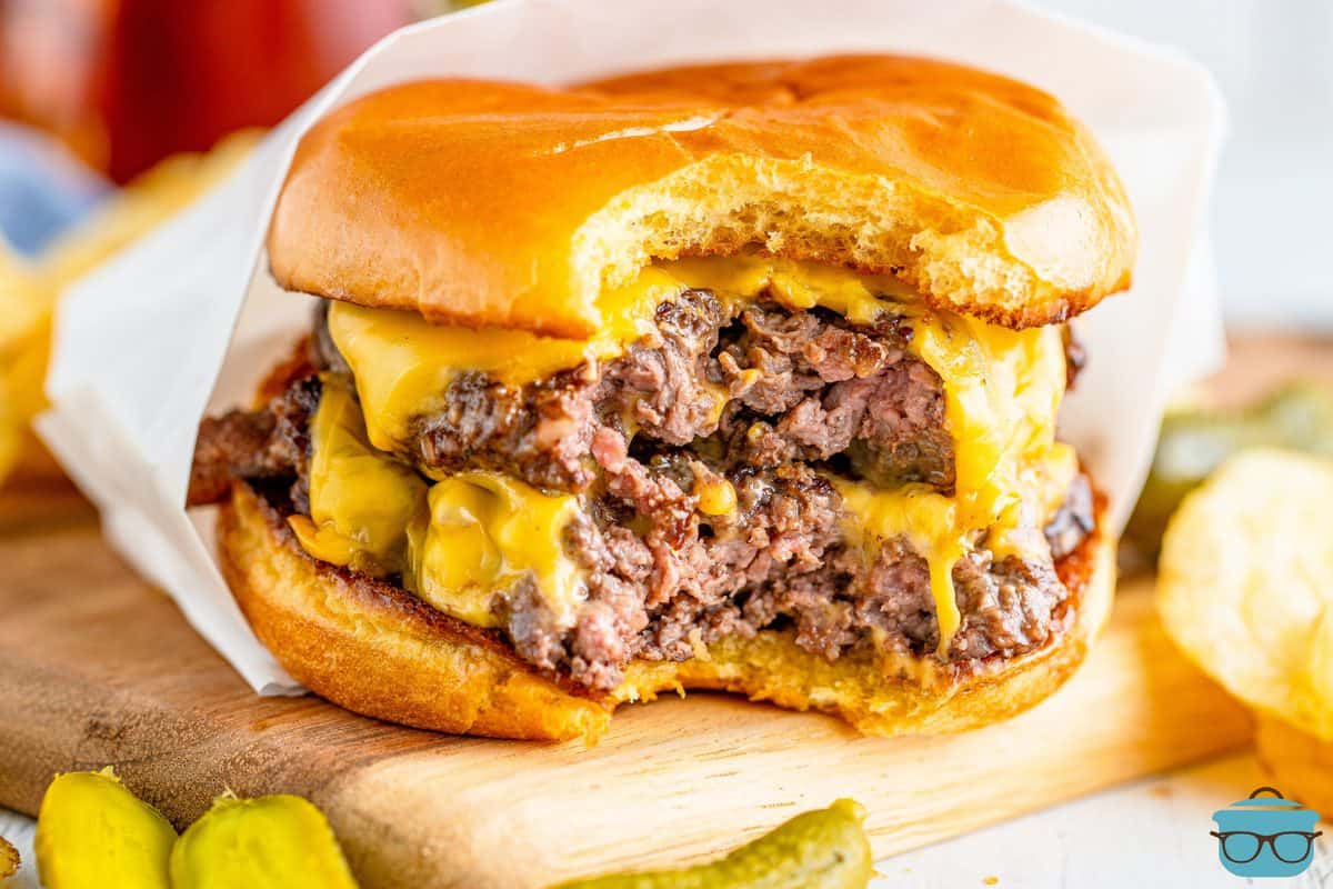 close up photo of a double cheeseburger on a bun with a bite removed