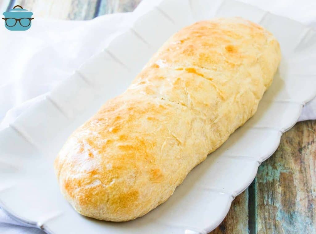 roll of homemade French bread on a white platter.