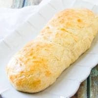 roll of homemade French bread on a white platter