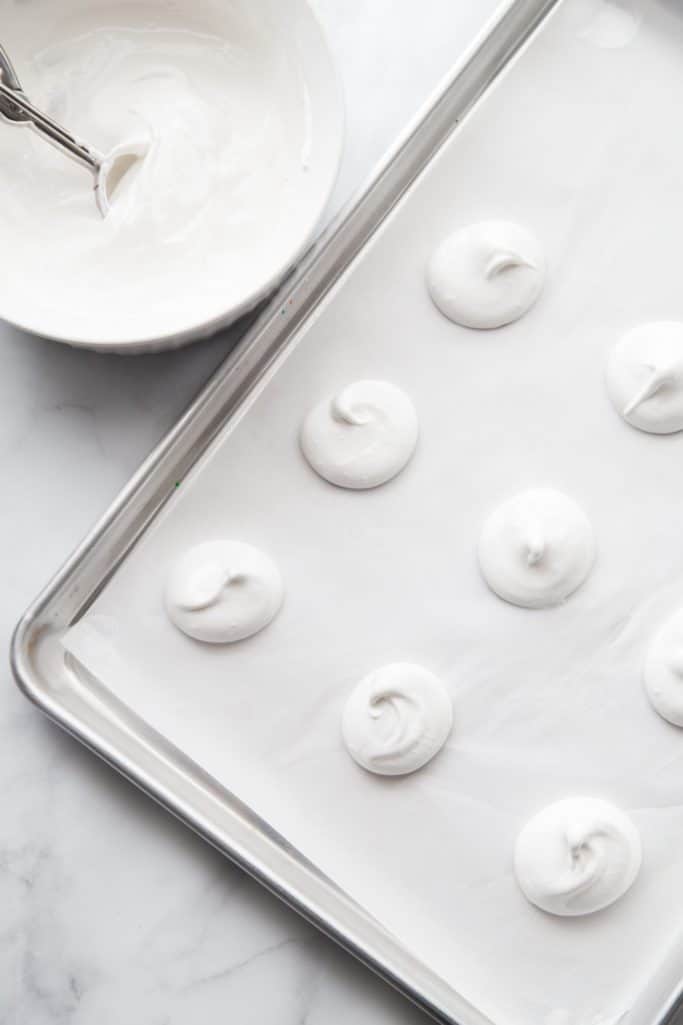 Homemade vanilla meringues before baking on a cookie sheet.