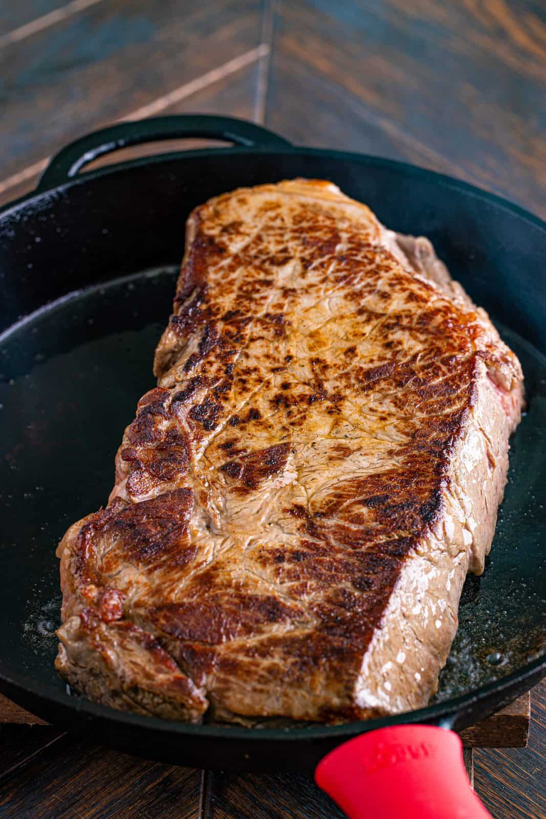 browning a round steak in a cast iron skillet. 