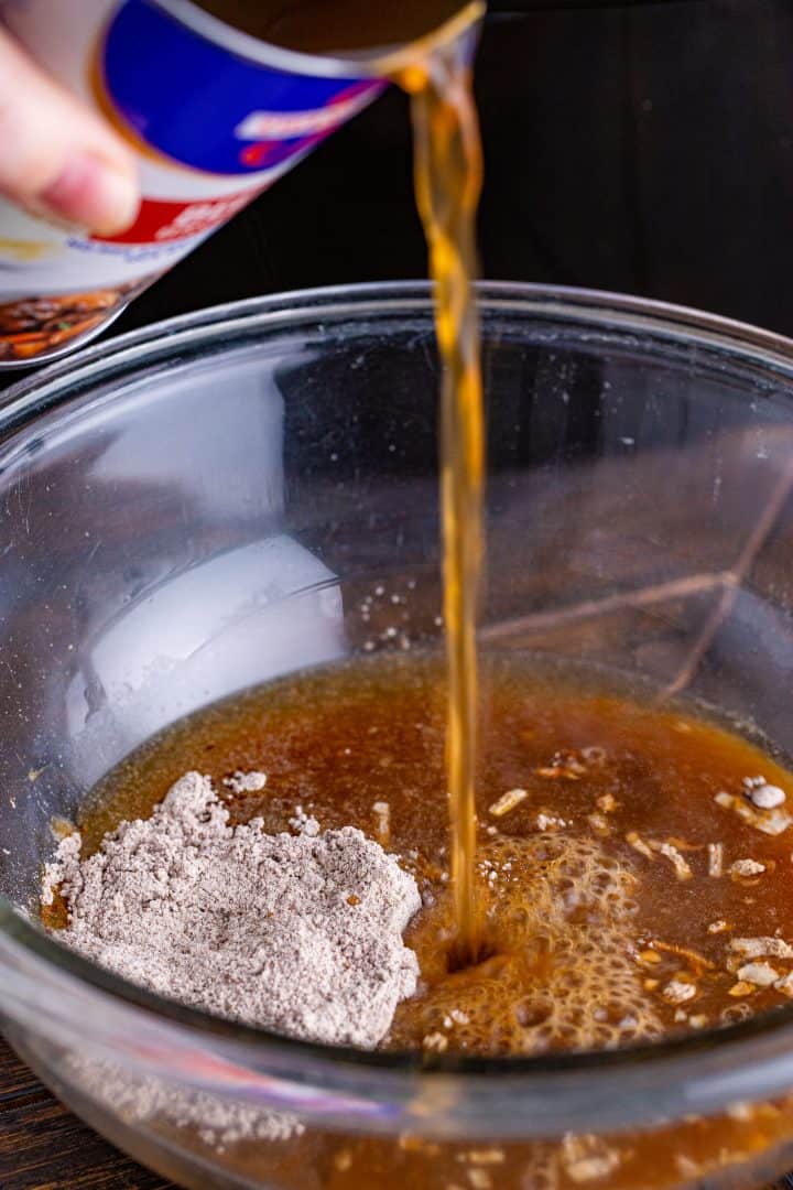beef broth shown being poured into a bowl along with seasonings. 