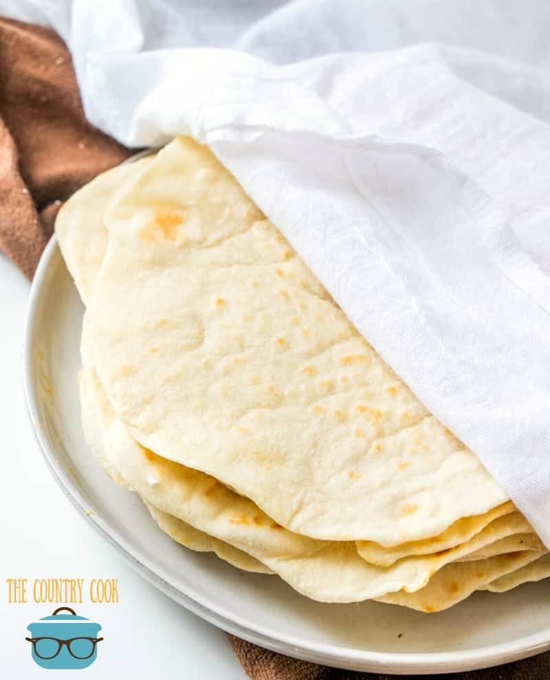 Homemade Flour Tortillas staying warm in between clean white dish towels.