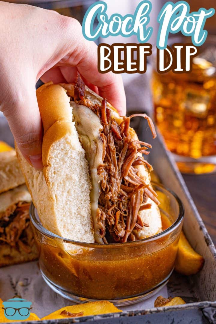 a Caucasian hand folding half a beef ip sandwich and dipping it into a bowl of au jus.