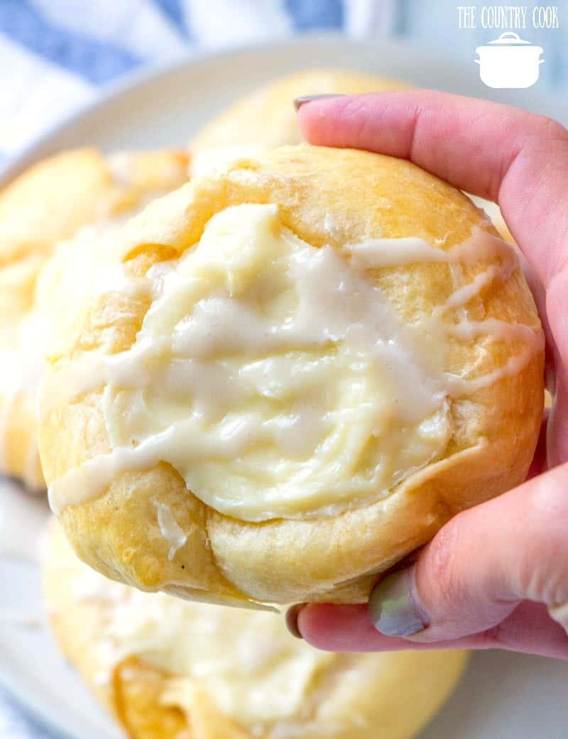 a hand holding up a cheese danish. 