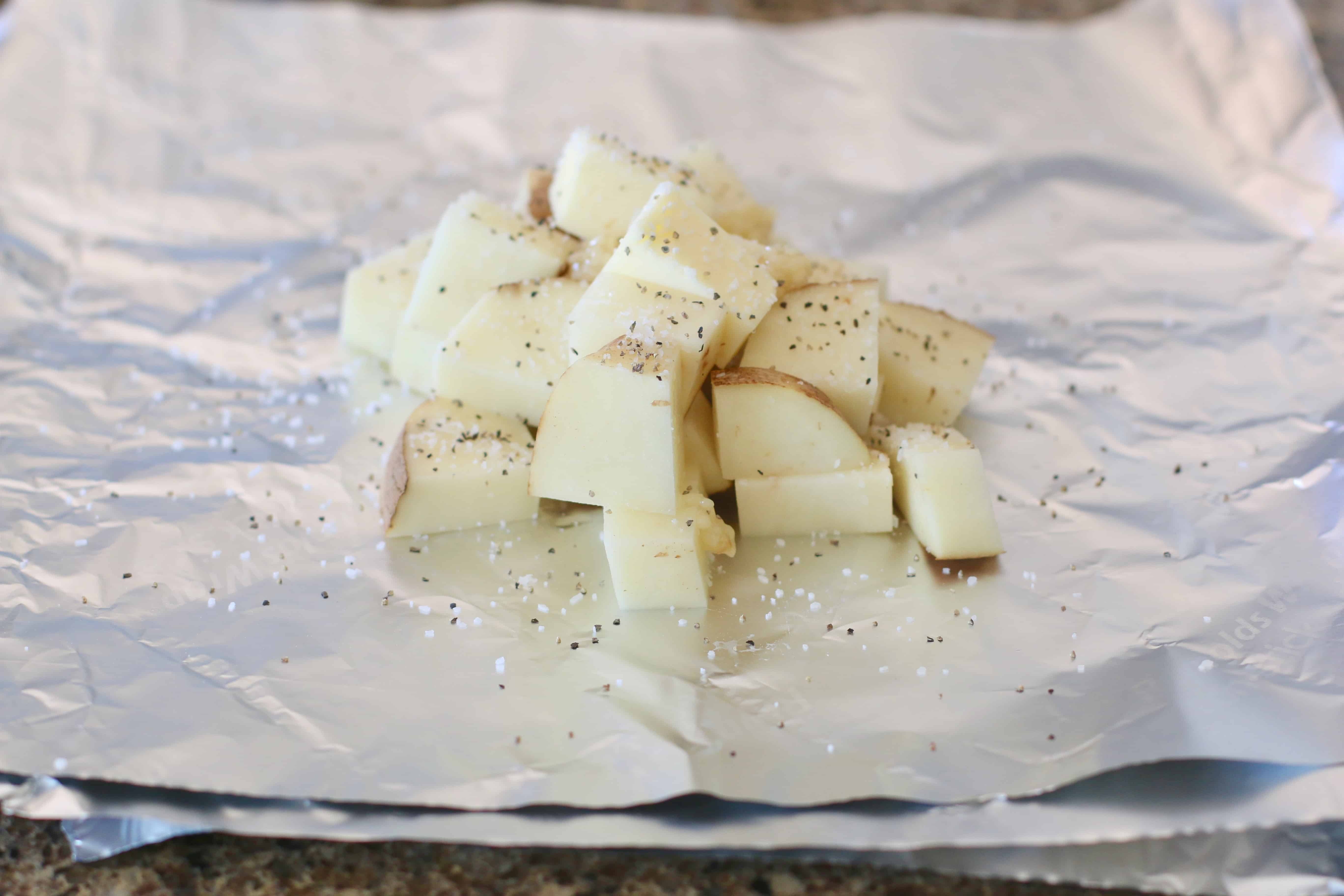 diced potatoes on aluminum foil with garlic, salt and pepper.
