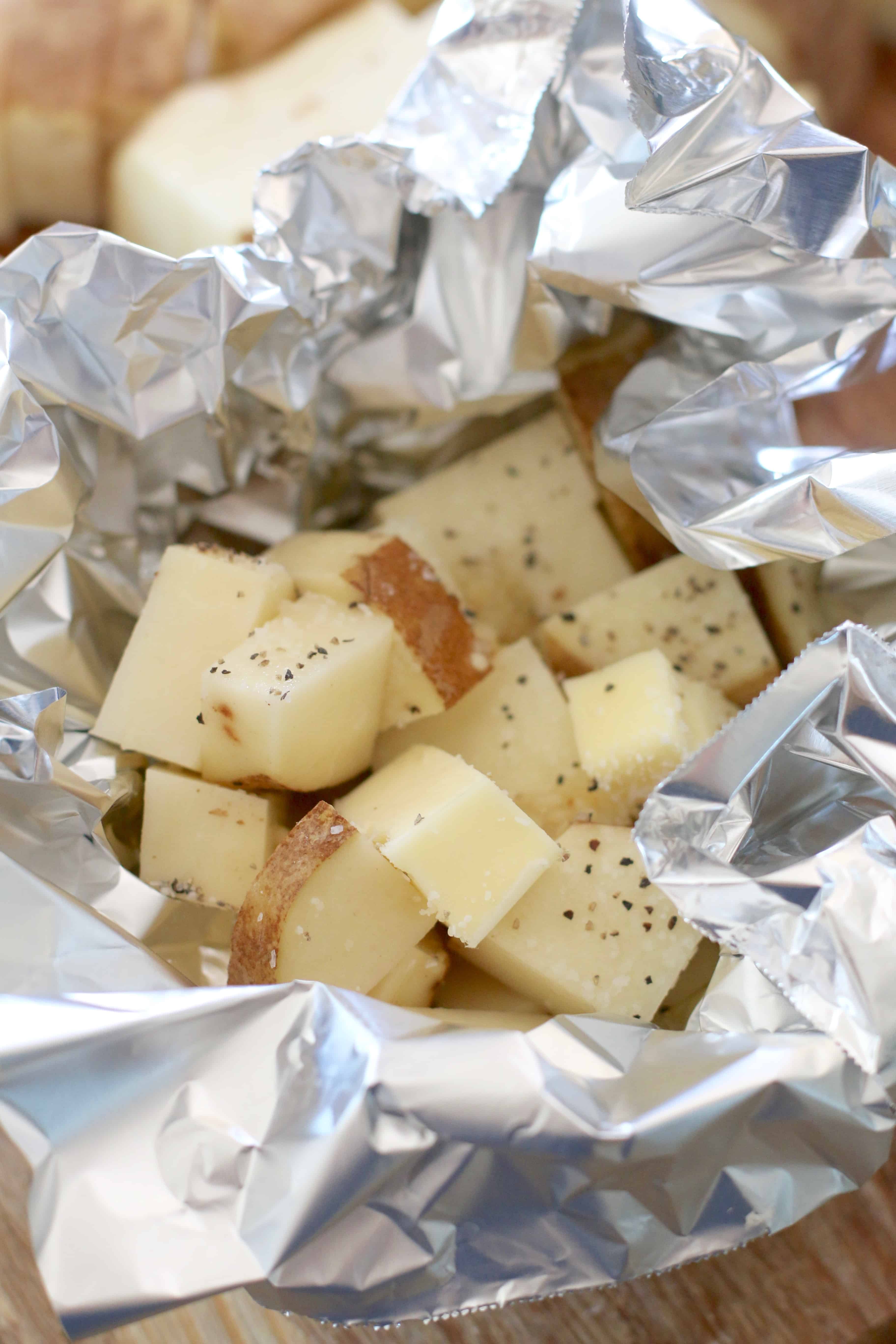 diced potatoes, butter and salt and pepper shown in aluminum foil.