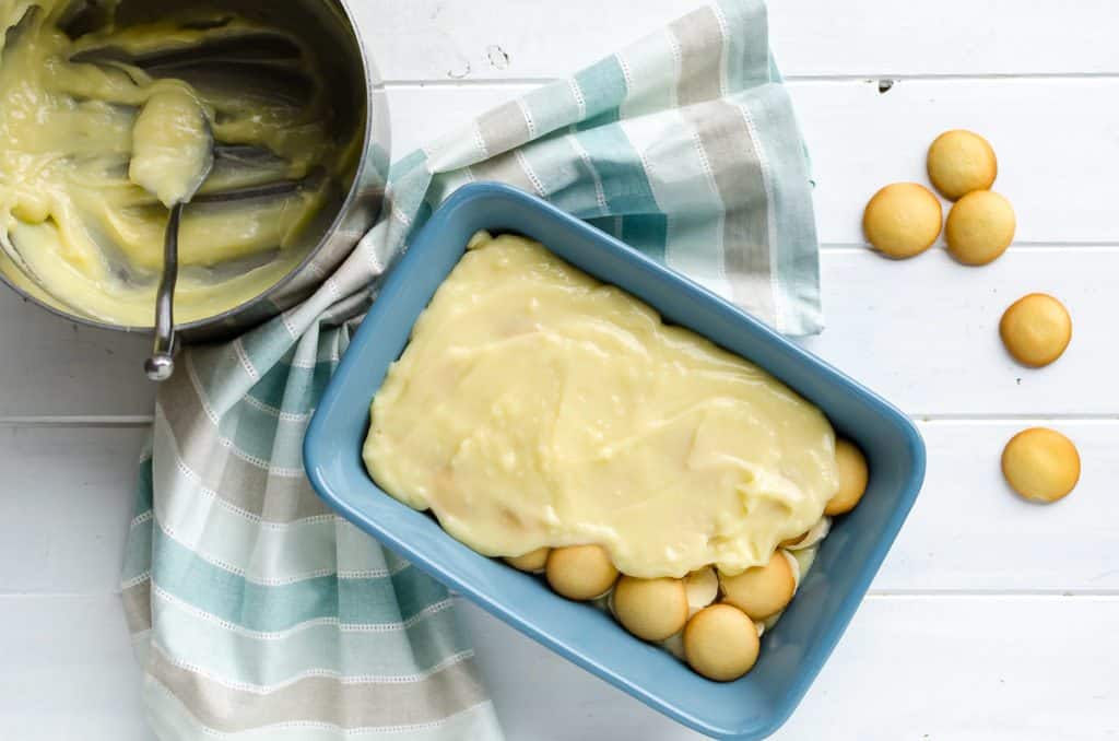 spreading homemade custard layer over sliced bananas and Nilla wafers in a 2-quaer casserole dish