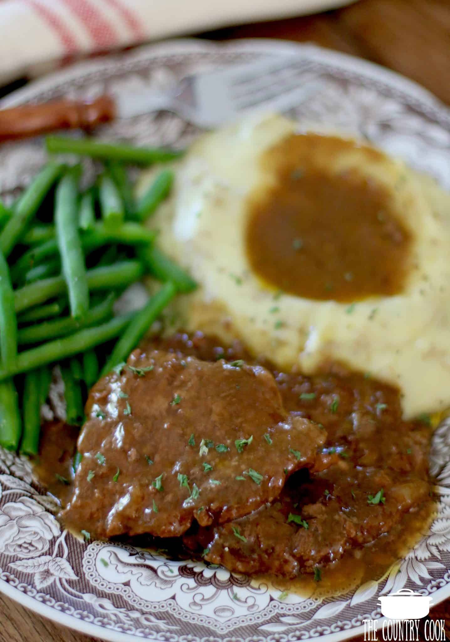Crock Pot Cube Steak and Gravy served with mashed potatoes and green beans.