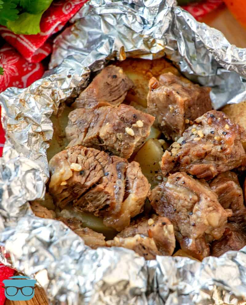 cooked steak and potatoes in aluminum foil.