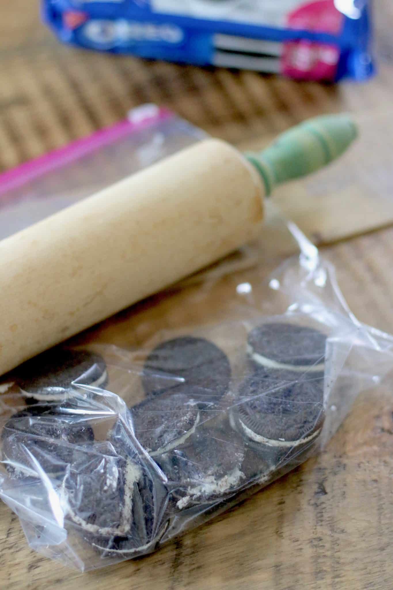 rolling pin crushing Oreos in a plastic bag.