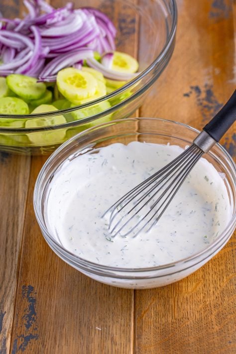 A creamy dressing in a bow with a whisk.