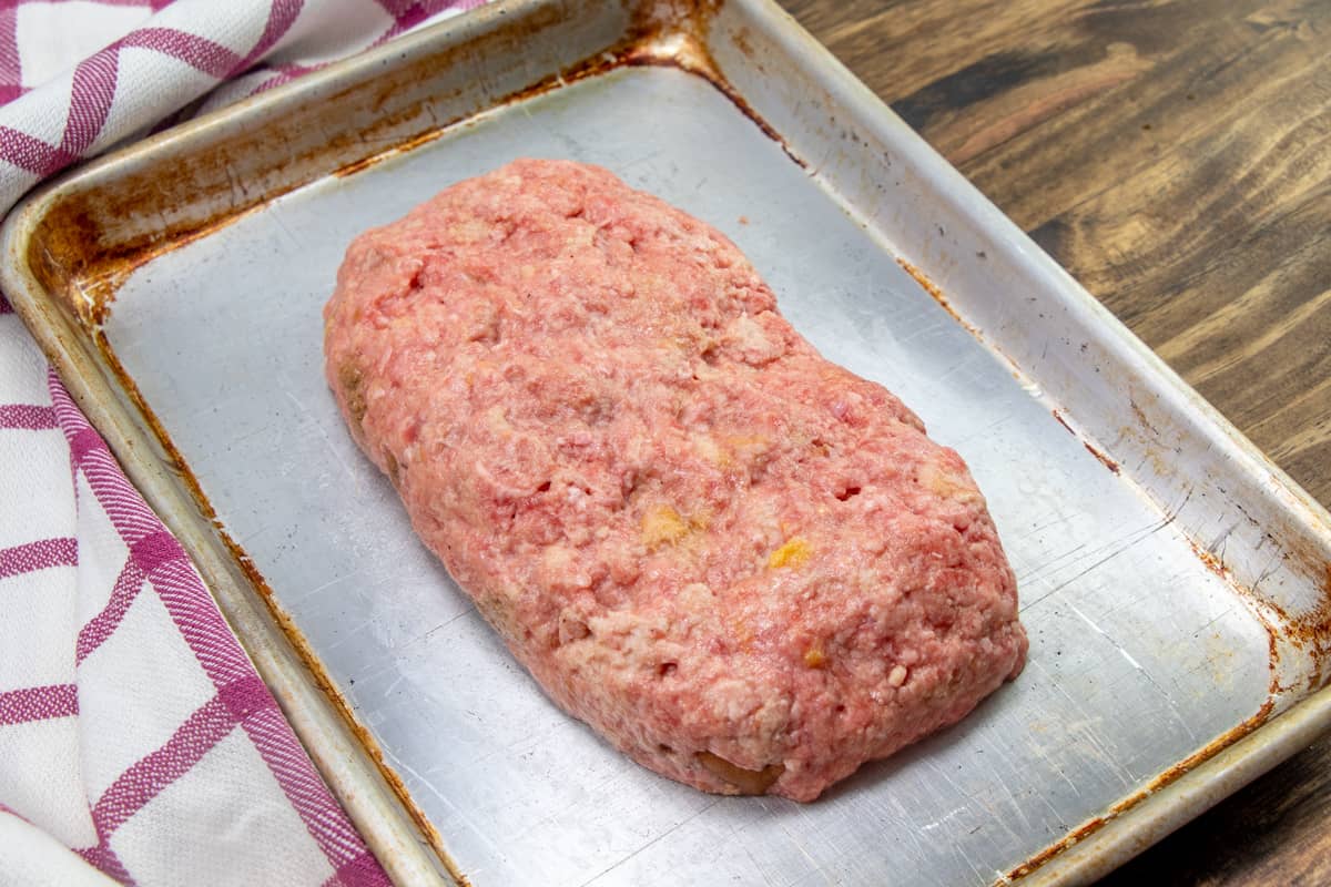 meatloaf spread into a loaf shape on a cookie sheet.
