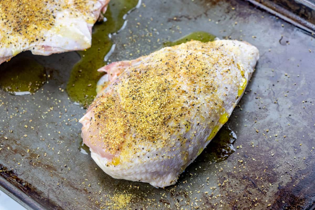 chicken breast on a baking pan seasoned with lemon pepper.
