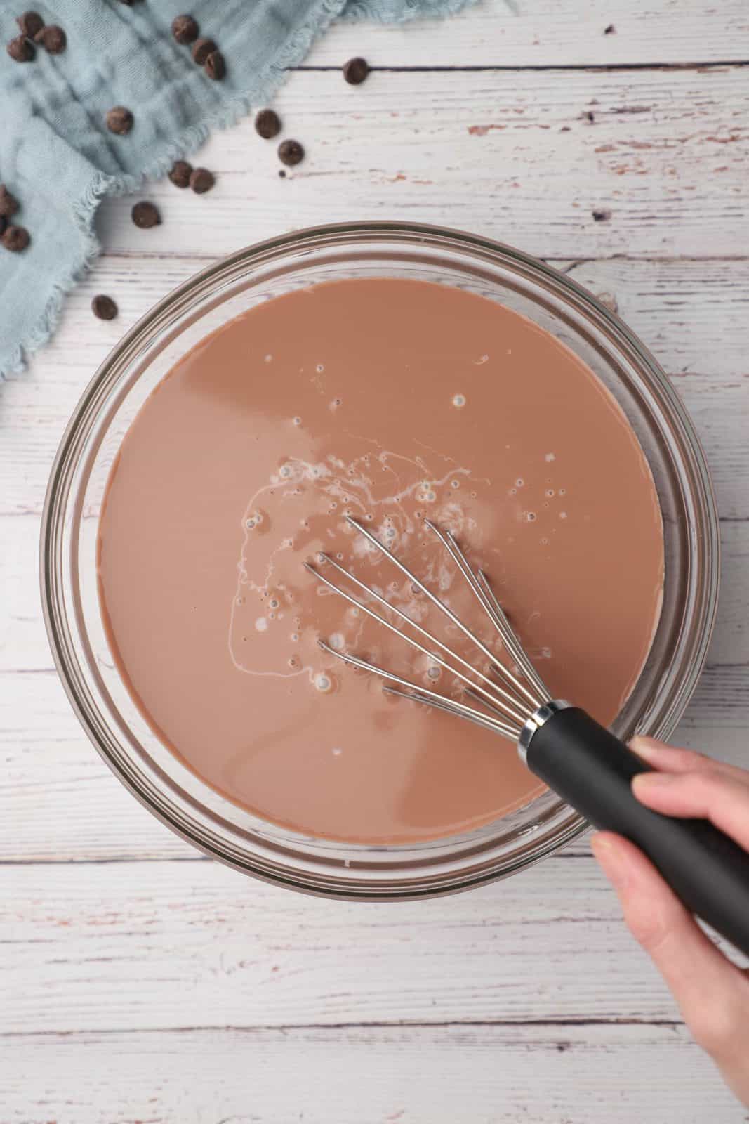 chocolate milk and sweetened condensed milk in a bowl with a whisk.