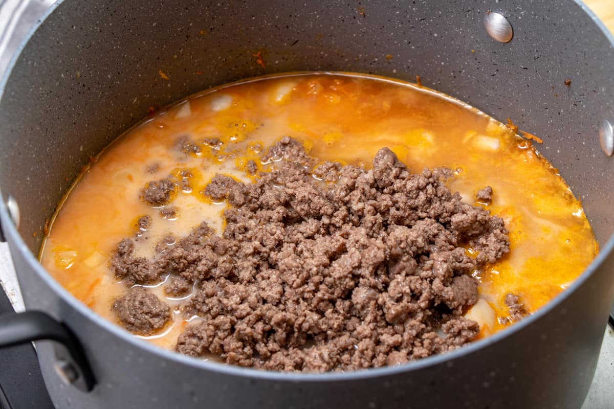 cooked ground beef added to soup mixture in a large pot.