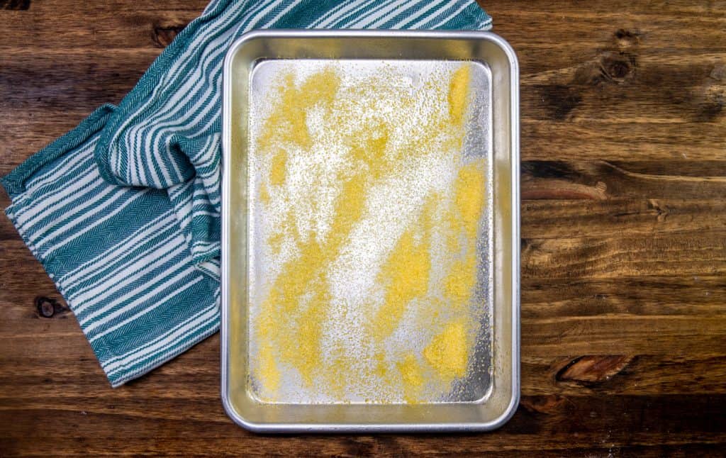yellow corn meal sprinkled on top of stainless steel baking sheet
