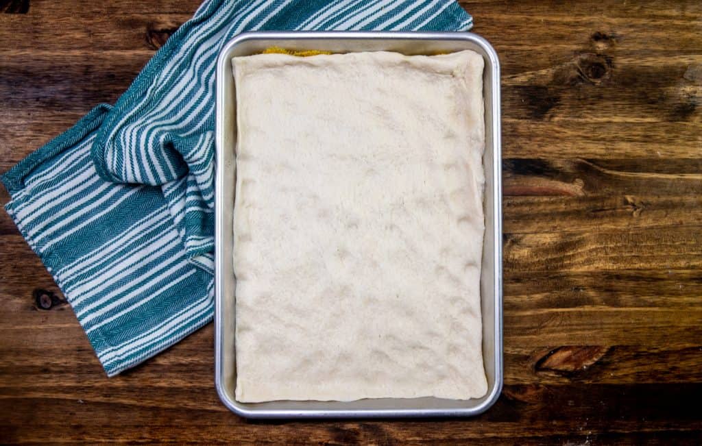 pizza dough spread out evenly onto baking sheet