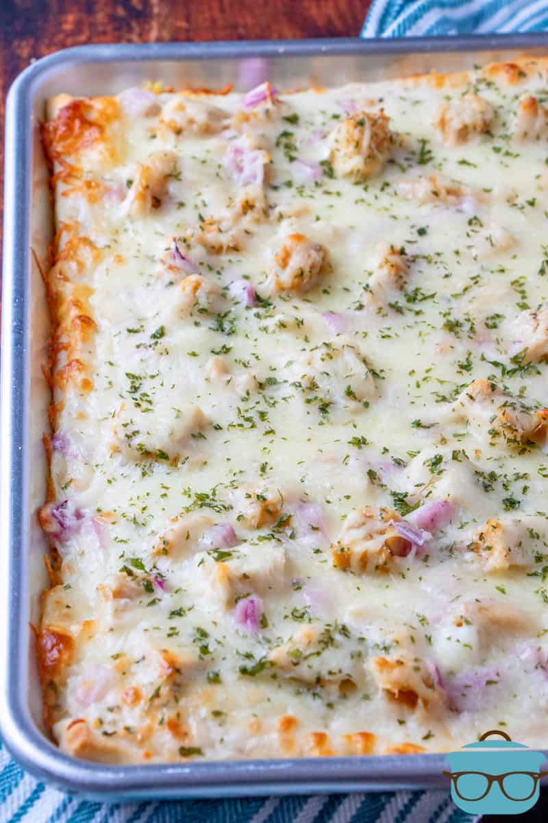 fully baked chicken Alfredo pizza on a stainless steel baking sheet.