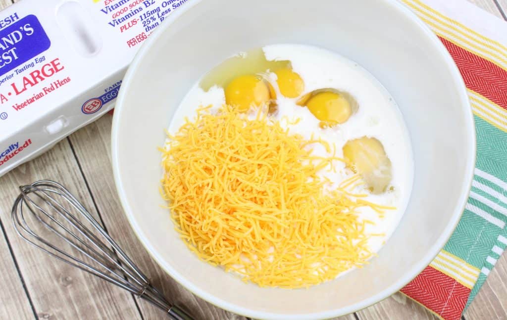 mixing bowl with eggs, milk and cheddar cheese