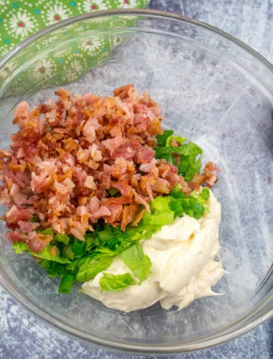 real mayonnaise, romaine lettuce, bacon and green onions mixed together in a clear bowl.