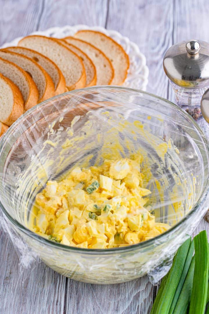 bowl of egg salad covered in plastic wrap.