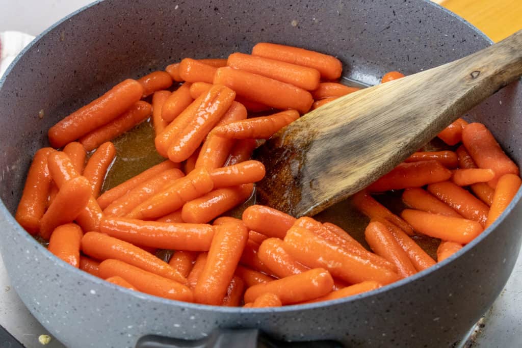 baby carrots added to large skillet with maple syrup, brown sugar and butter.
