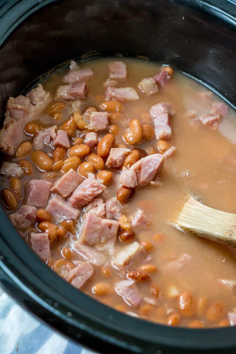 slow cooker soup beans and ham in an oval crock pot.