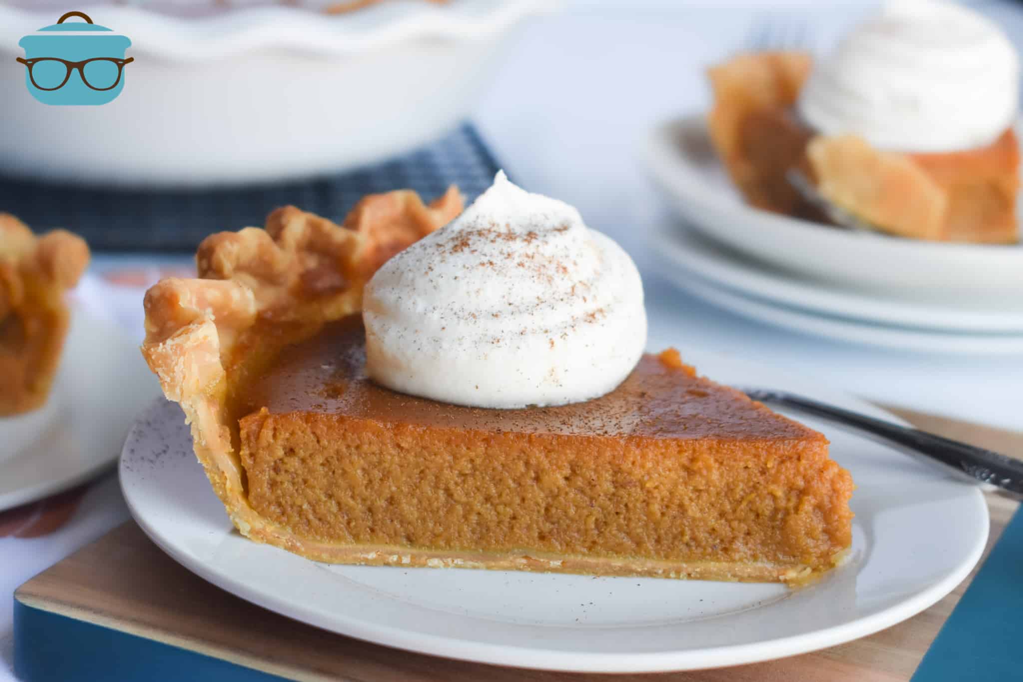 slice of pumpkin pie on a small white plate, topped with a dollop of whipped cream.