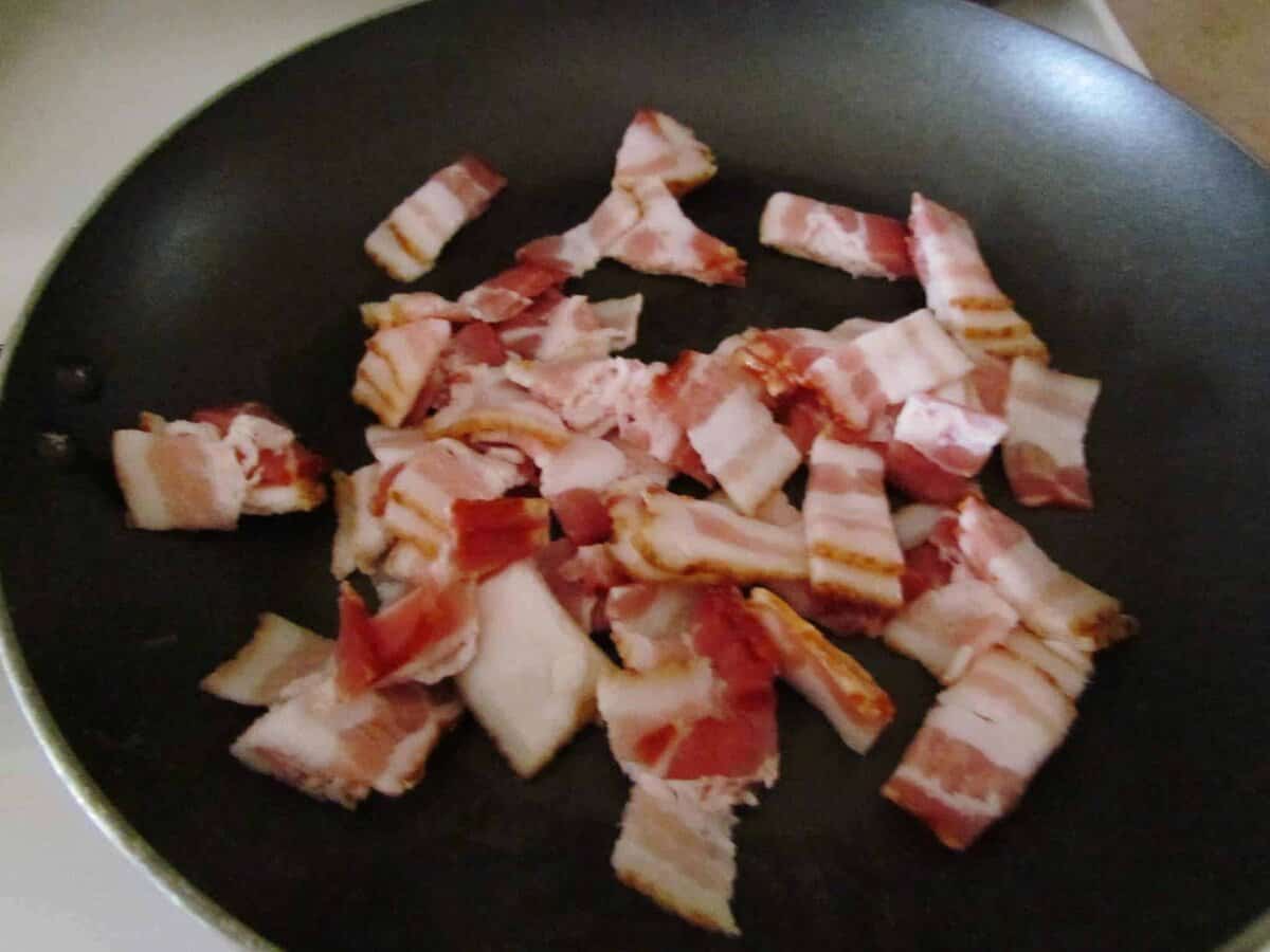 frying chopped bacon in a pan.