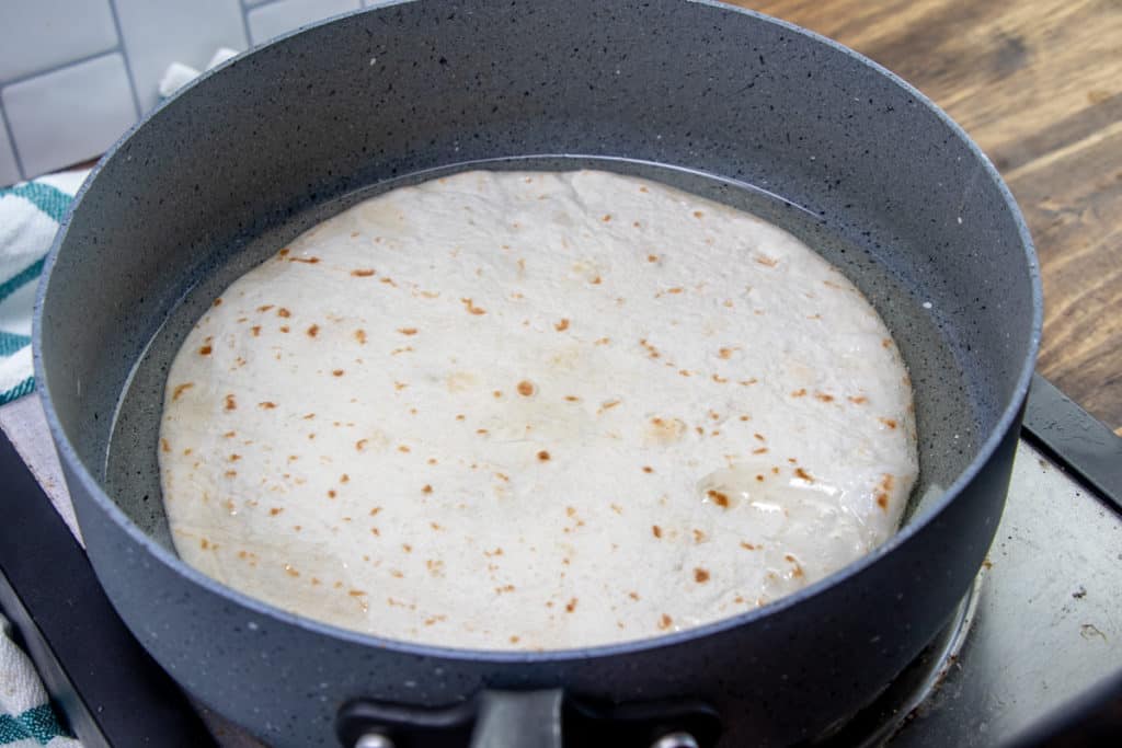 frying flour tortillas in hot oil in a large skillet