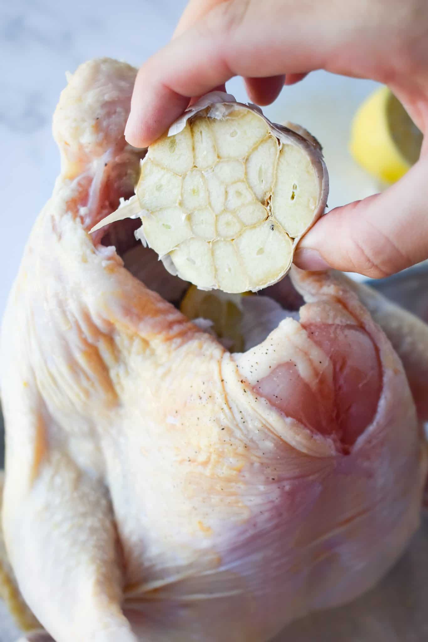 adding a sliced head of garlic into the cavity of a fresh chicken.