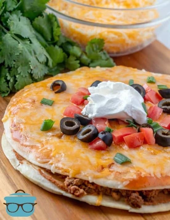 Taco Bell Mexican Pizza ropped with tomatoes and sliced olives and sour cream
