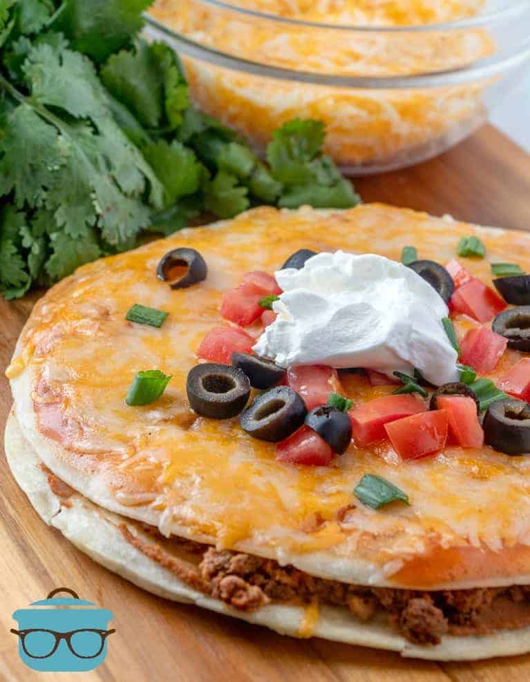 Taco Bell Mexican Pizza ropped with tomatoes and sliced olives and sour cream