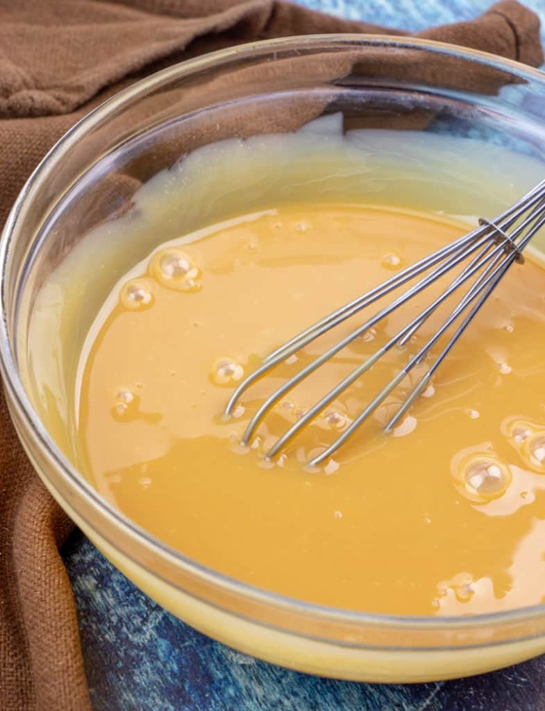 sweetened condensed milk combined with caramel ice cream topping a bowl.