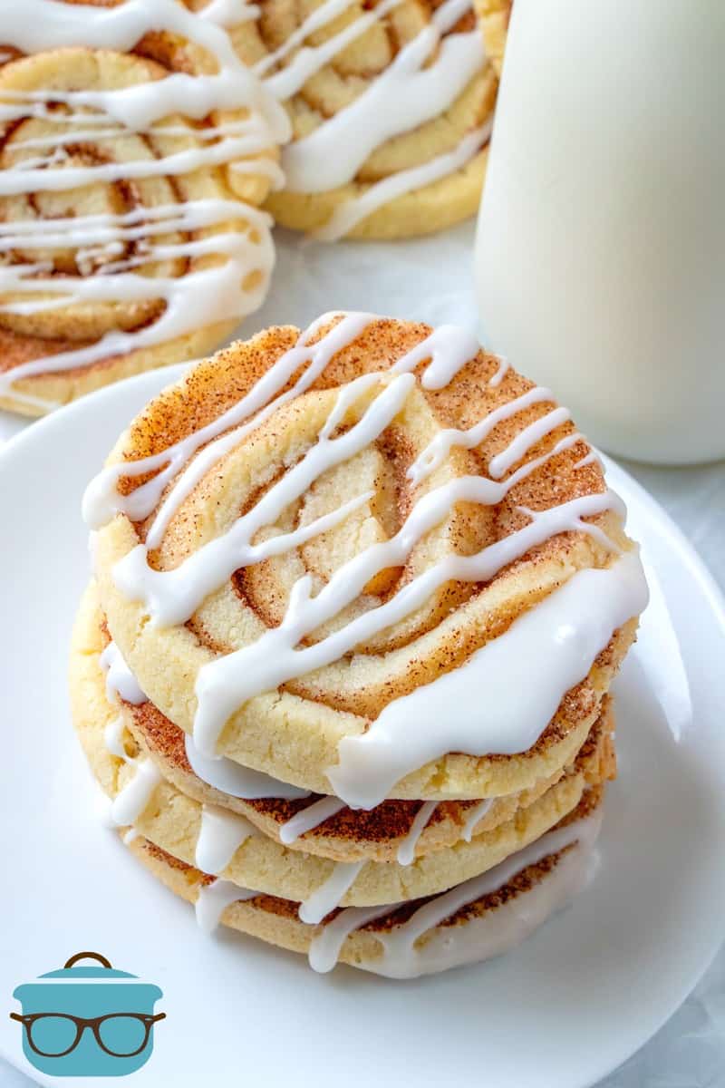 Cinnamon Roll Cookies stacked on a white plate served with a bottle of cold milk
