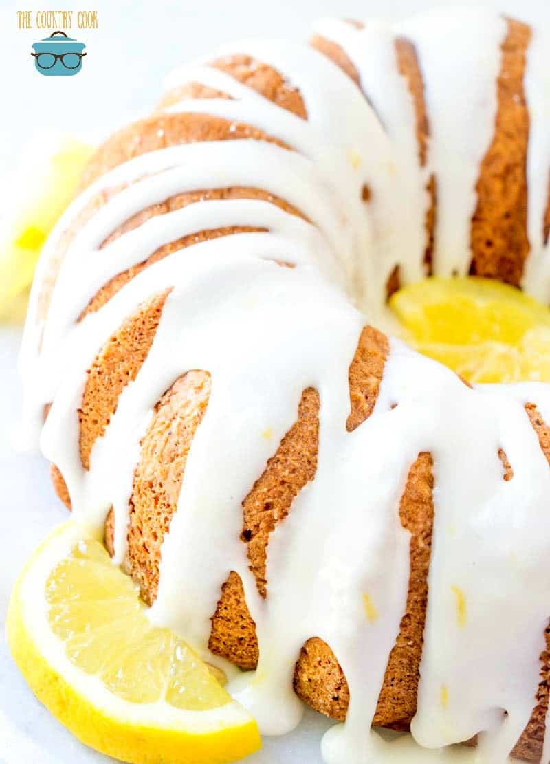 7Up Cake with lemon icing drizzled on top with fresh lemon slices around cake.