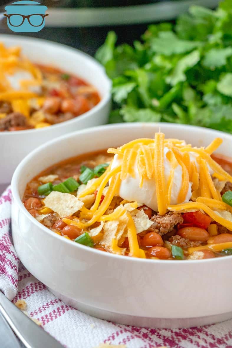 Crock Pot Taco Soup in a bowl served with tortilla chips, sour cream and shredded cheese.