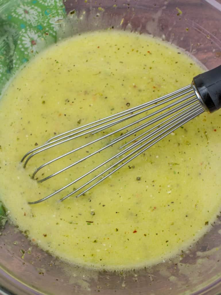 Copycat Olive Garden Salad Dressing, made from scratch shown being whisked in a glass bowl