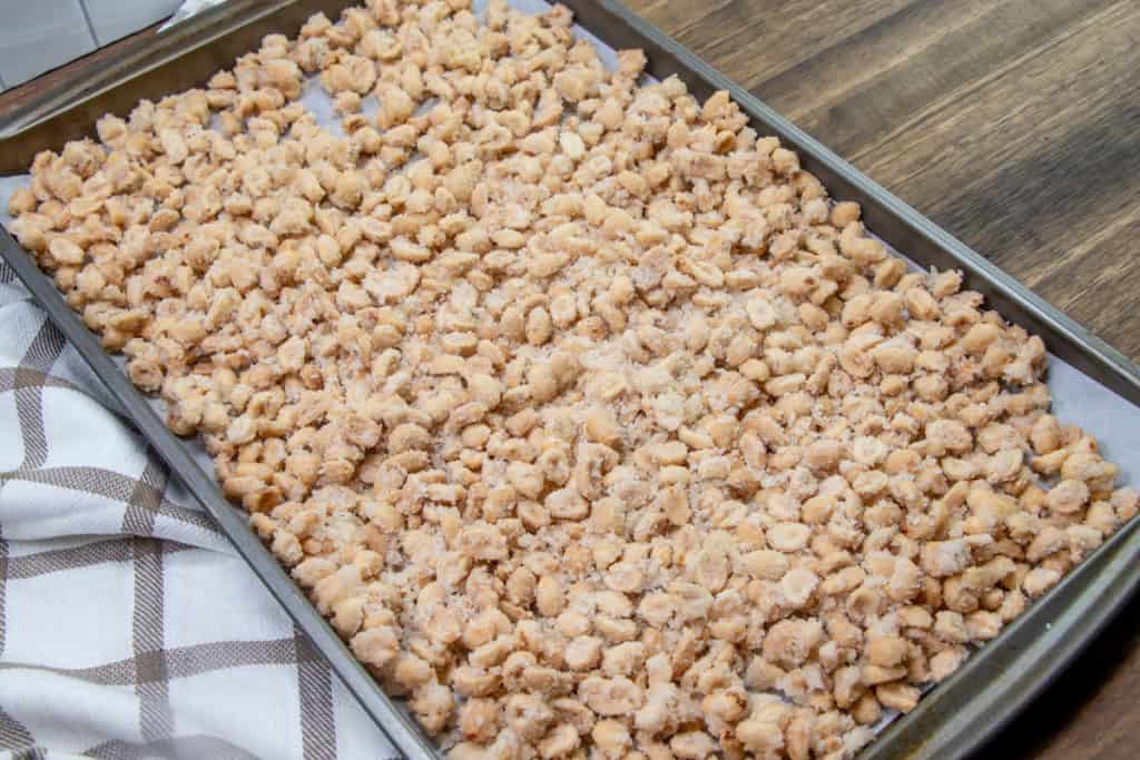 sugar coated peanuts spread into a single layer on a cookie sheet.